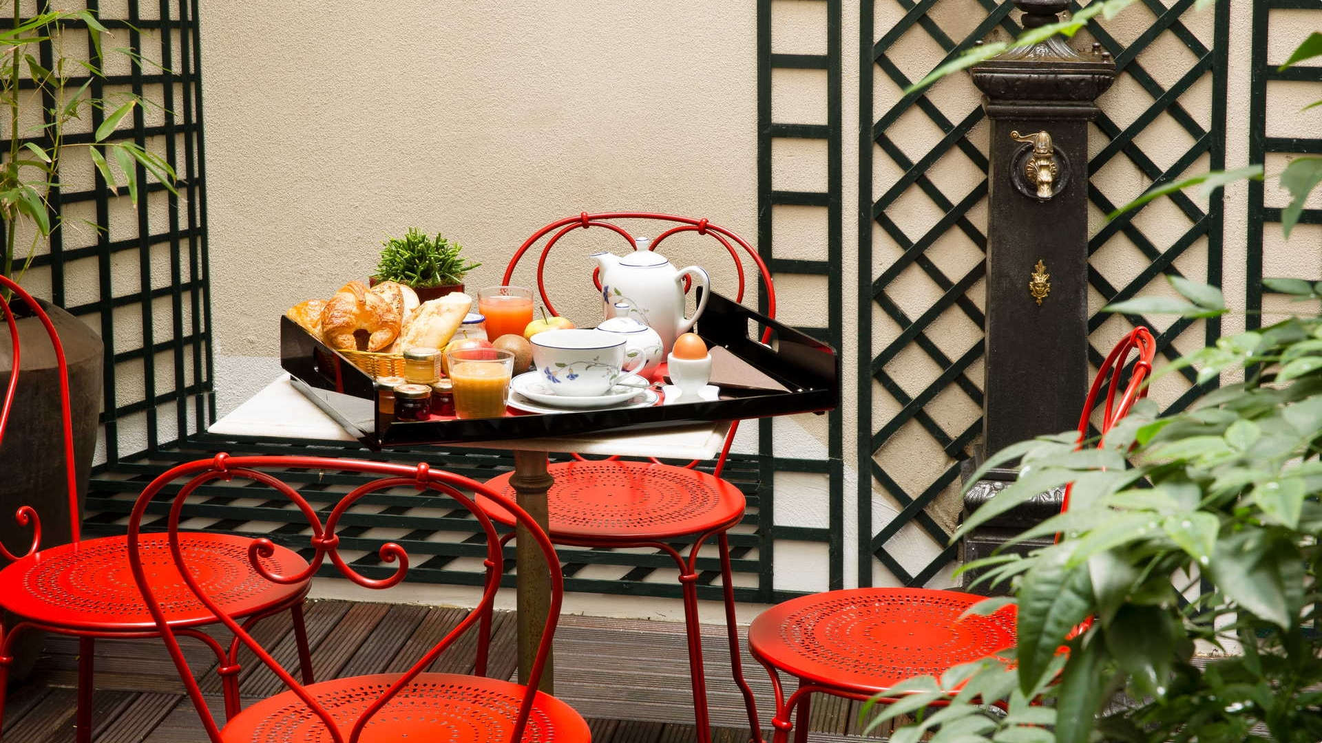 Petit déjeuner en terrasse avec chaises rouges, ambiance parisienne Hôtel Paris Centre, Hôtel Relais Madeleine